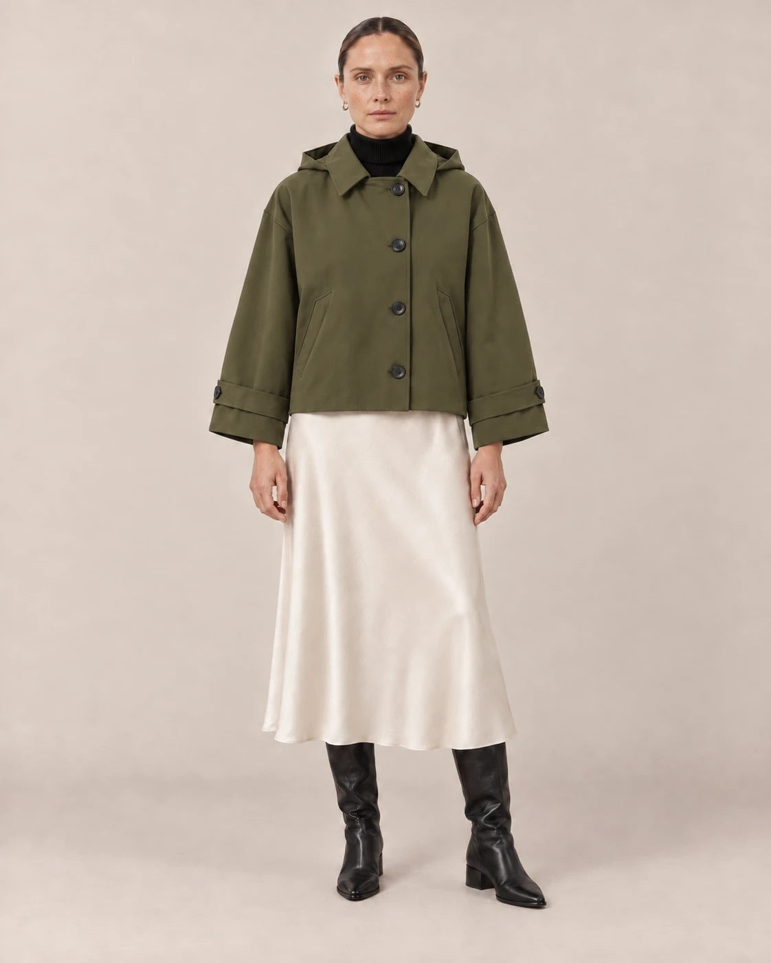 Chaqueta corta verde militar con capucha y falda midi de satén crudo
