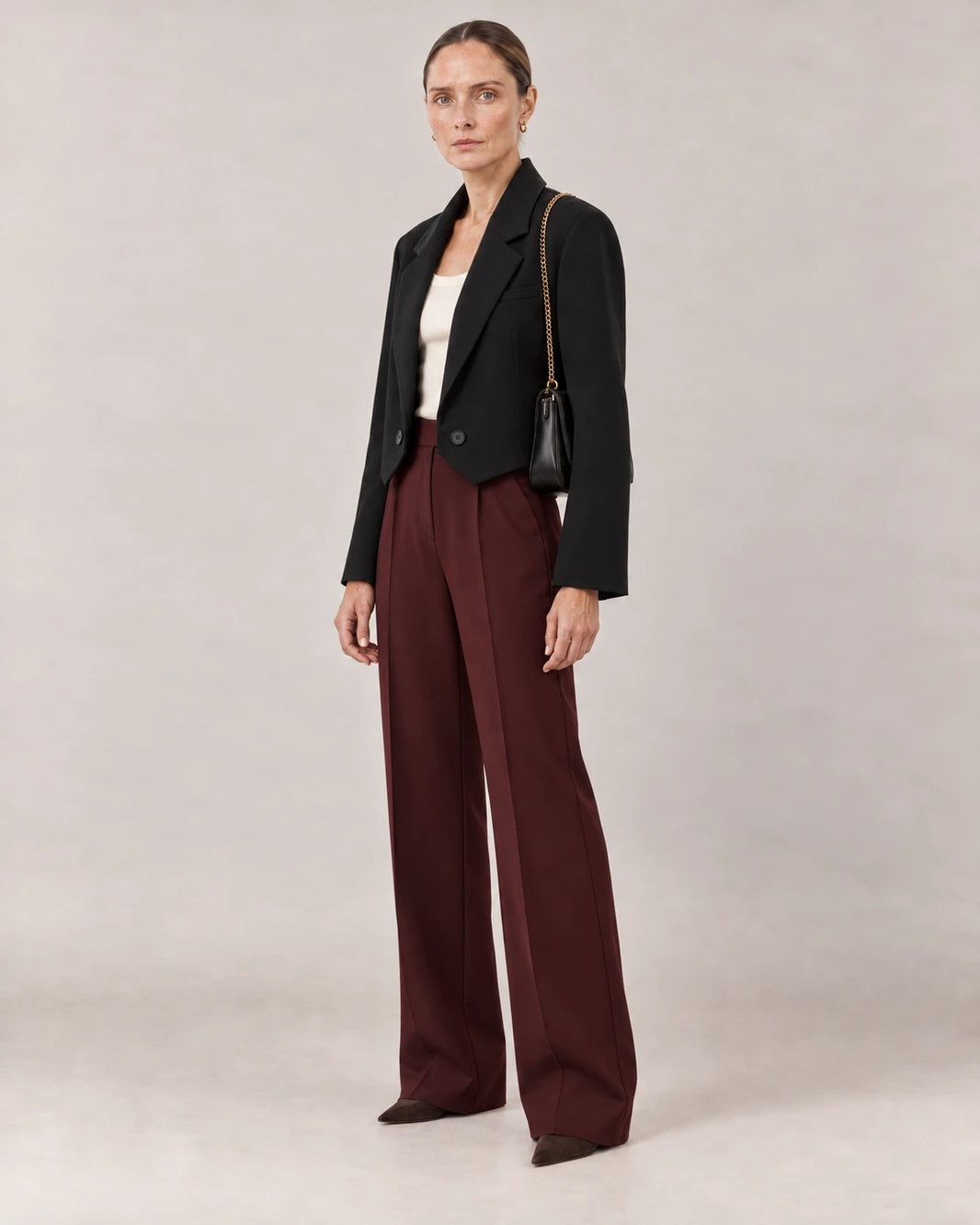 Blazer corto negro visto de tres cuartos con bolso negro de cadena dorada