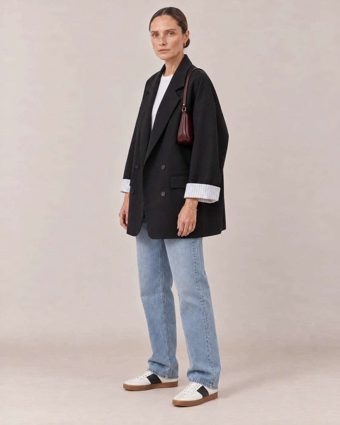 Blazer cruzado oversize negro visto de tres cuartos con bolso granate