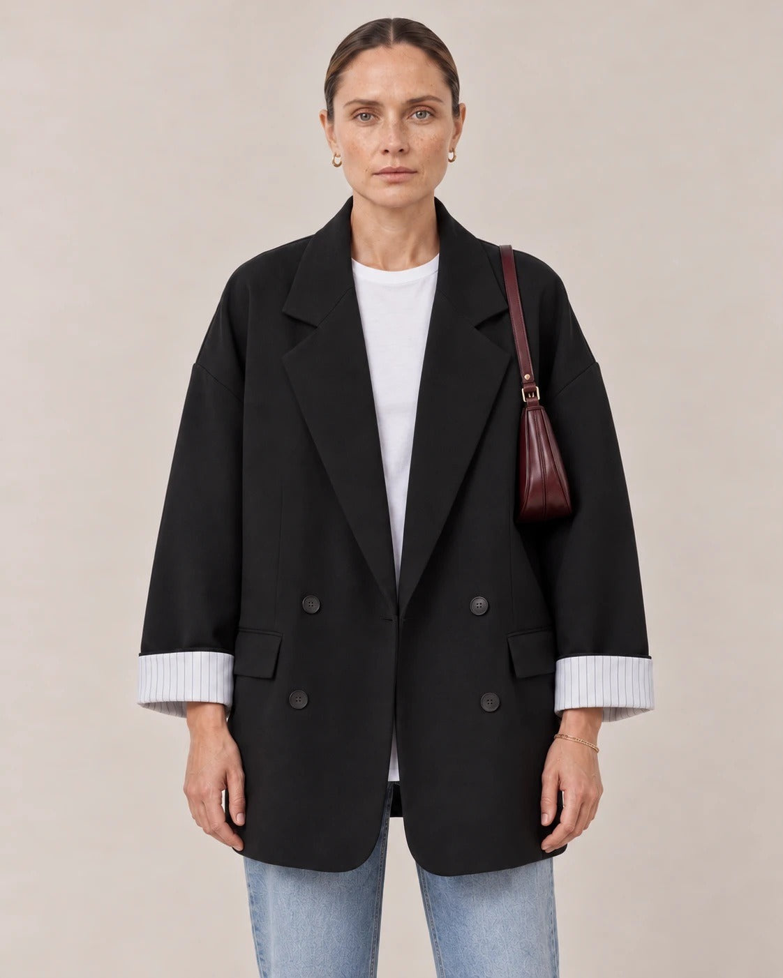 Detalle de las solapas, los cuatro botones y las mangas remangadas con forro a rayas del blazer negro
