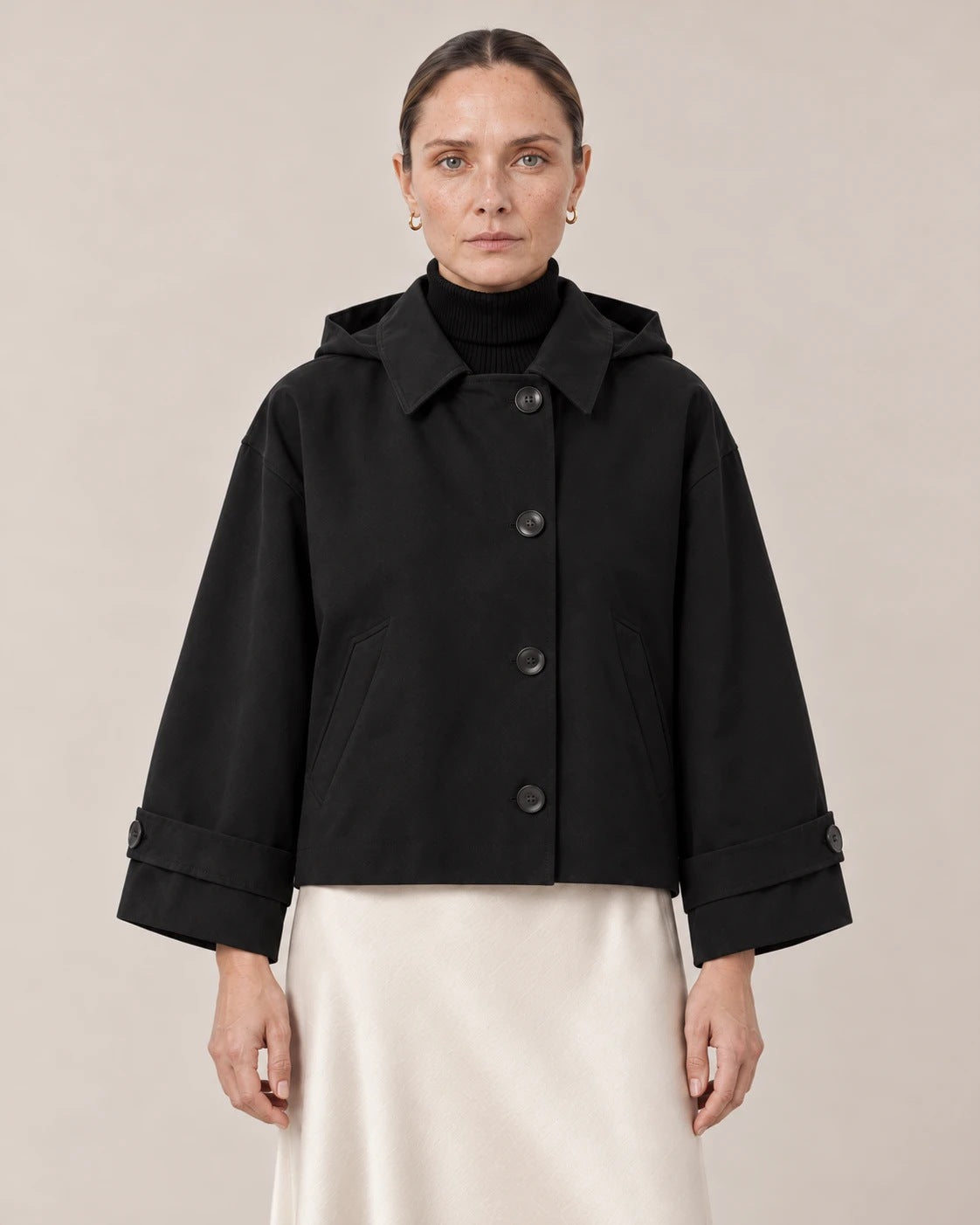 Detalle del cuello camisero, la capucha y los botones de la chaqueta negra