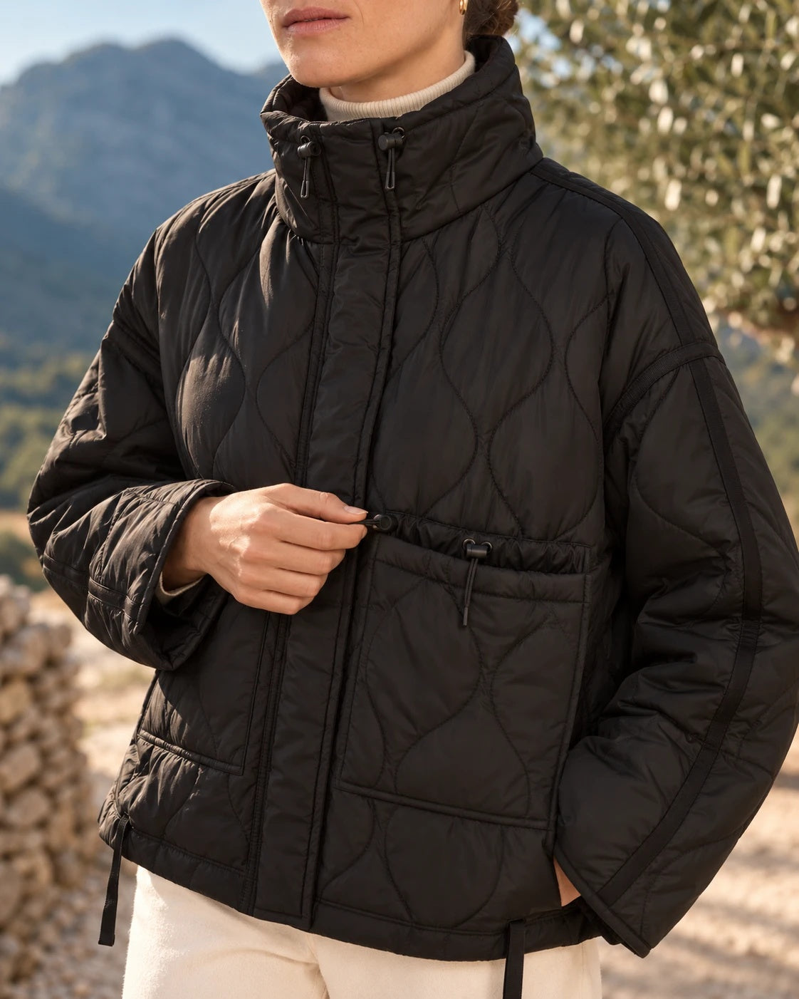 Detalle del cuello con topes y del bolsillo con cordón del chaquetón negro satinado