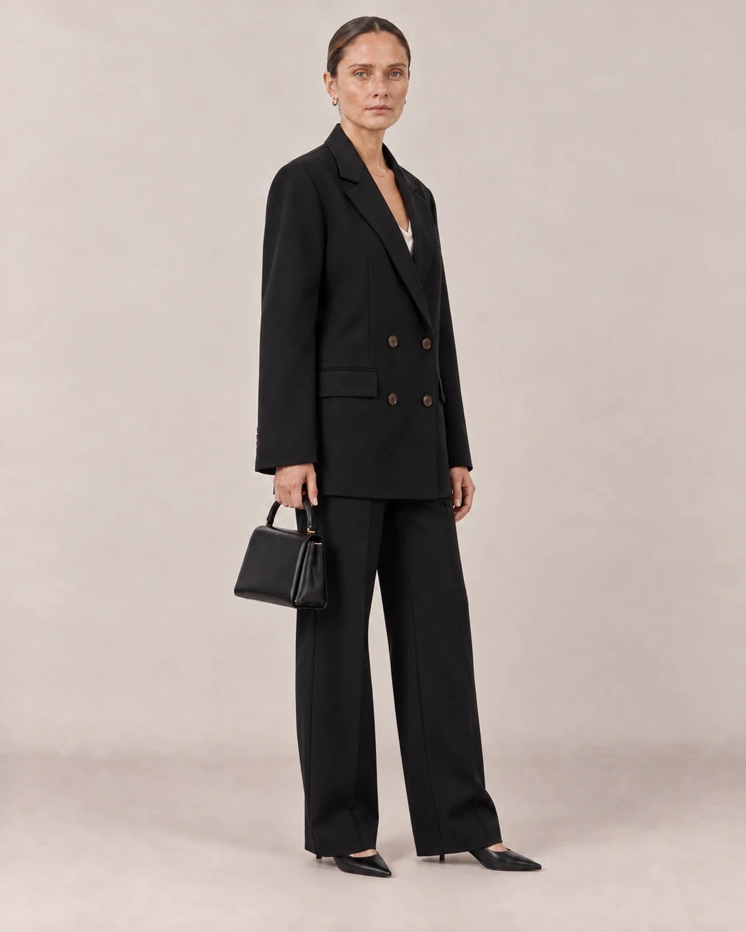Traje negro de americana cruzada visto de tres cuartos con bolso negro