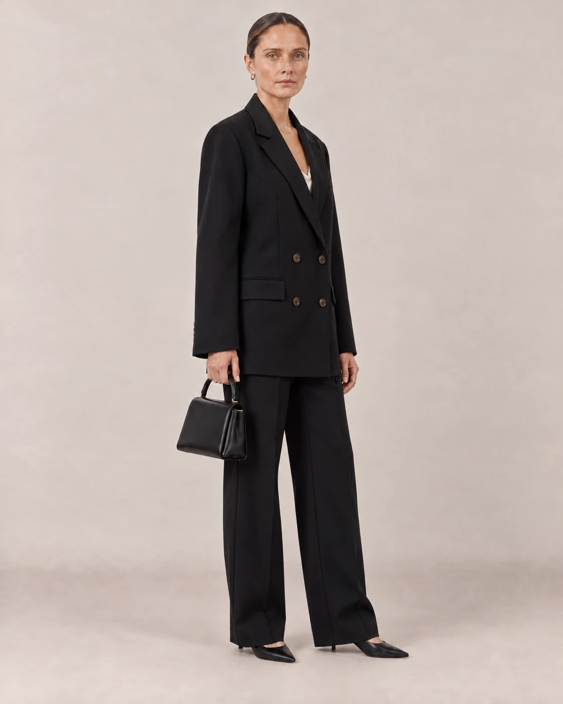 Traje negro de americana cruzada visto de tres cuartos con bolso negro